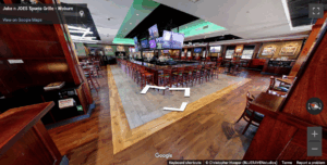 Spacious bar area at Jake n JOES Woburn with a large central bar, red stools, and multiple TVs.
